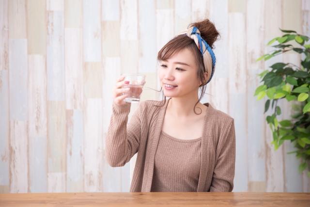 コップで水を飲む女性