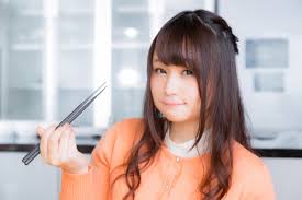 箸で食べている女性